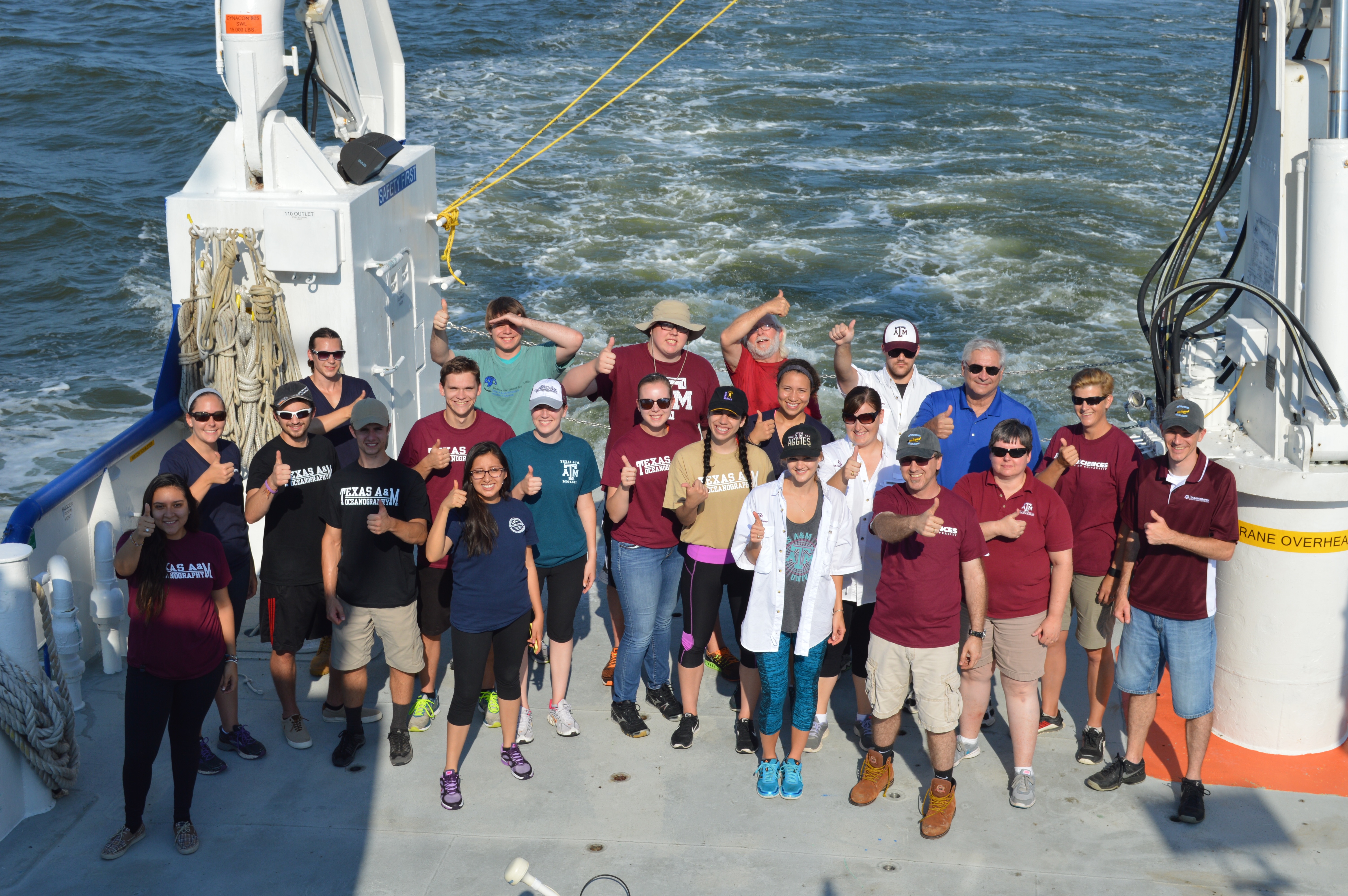 REU students on a cruise holding the Department of Oceanography flag